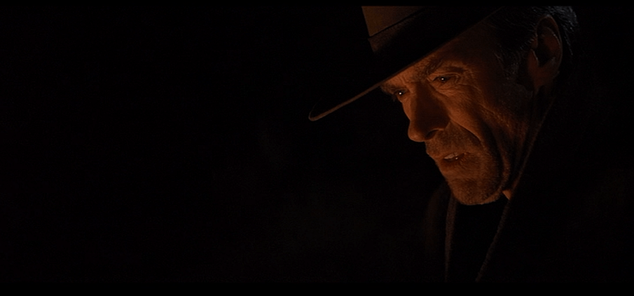 Clint Eastwood stares ruefully into a campfire in the movie Unforgiven Warner Bros Malpaso Productions